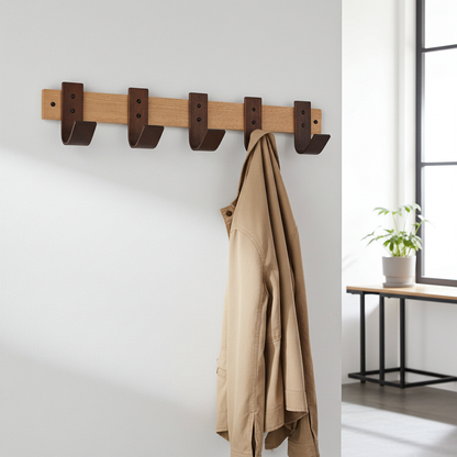 Wooden coat rack with brown hooks on a white wall, with a beige coat hanging on it.