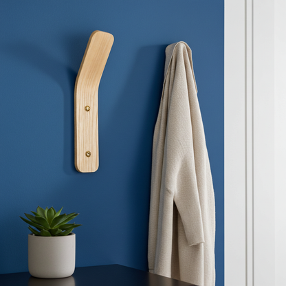 Wooden coat rack with a towel against a blue wall, next to a potted plant.
