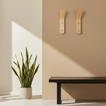 Minimalist interior with a plant, bench, and wooden wall hooks on a beige wall.