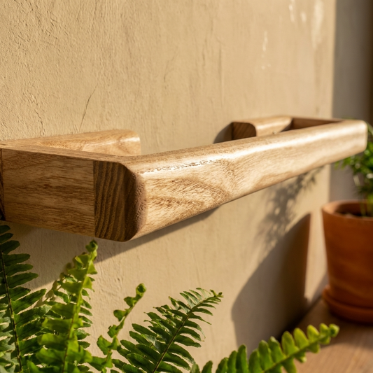 Wooden plant holder against a beige wall with greenery around with towel rail on wall